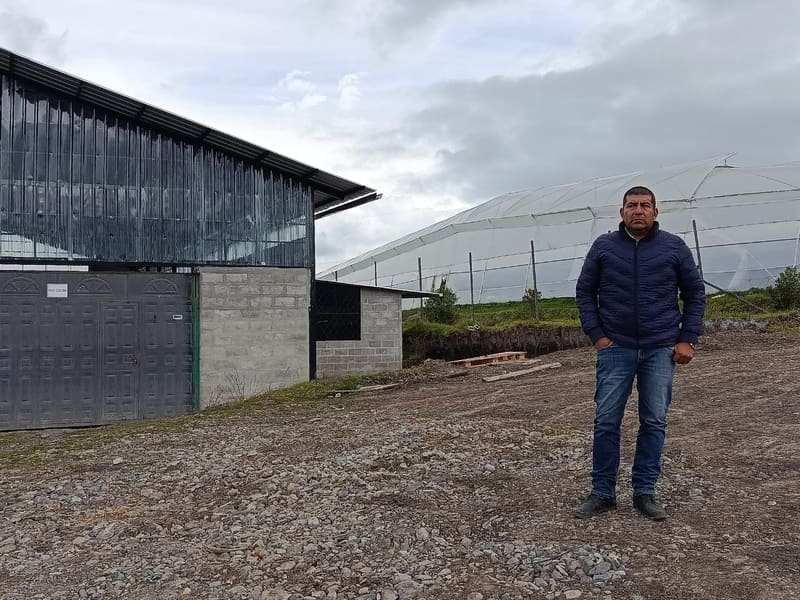 Manuel Chamba, founder of Cielos de América EC, in front of the post-harvest building and greenhouses